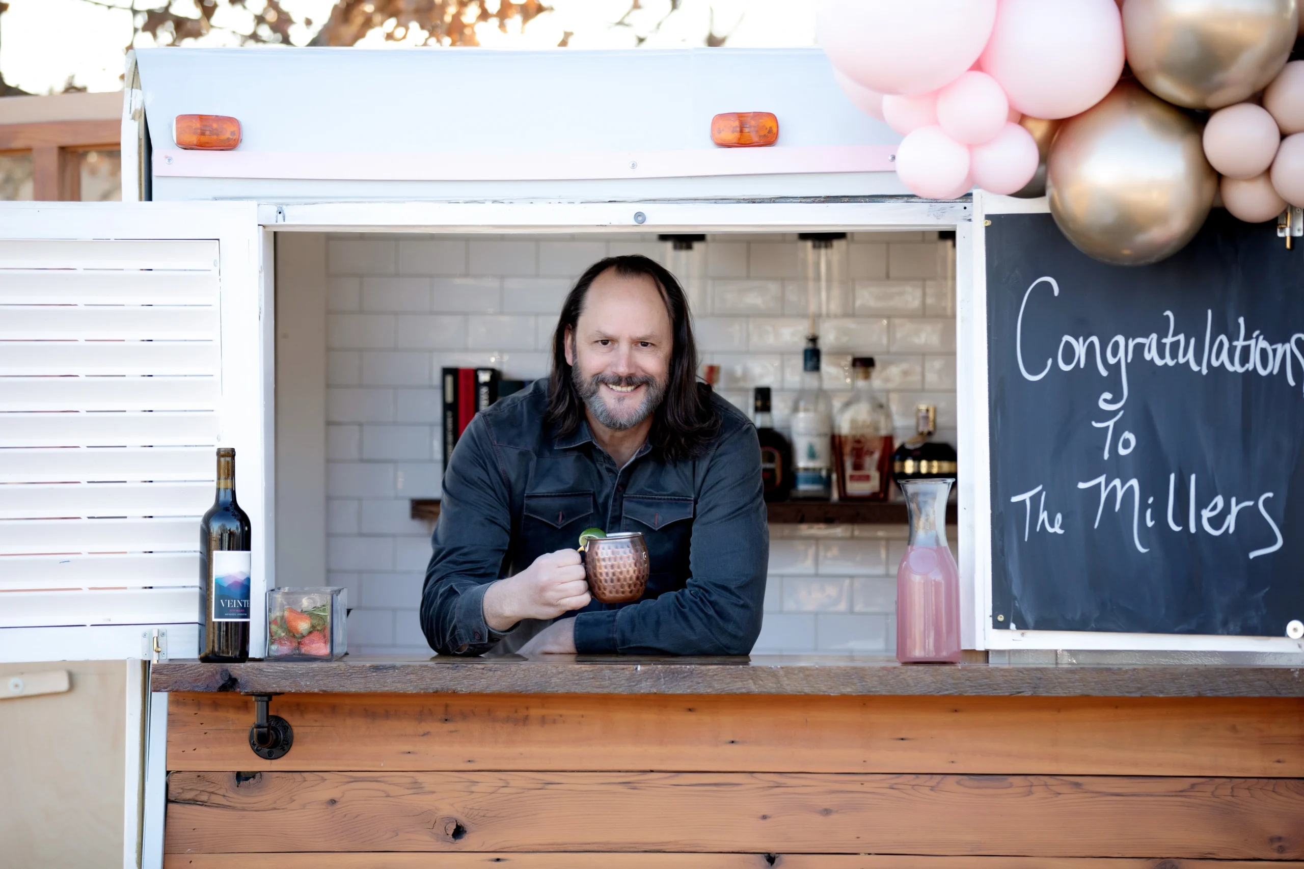 Shannon Vaughan, co-owner of Mixie Chix Mobile Bar, standing at the renovated vintage trailer bar he built and hauls for events across the Dallas–Fort Worth area.