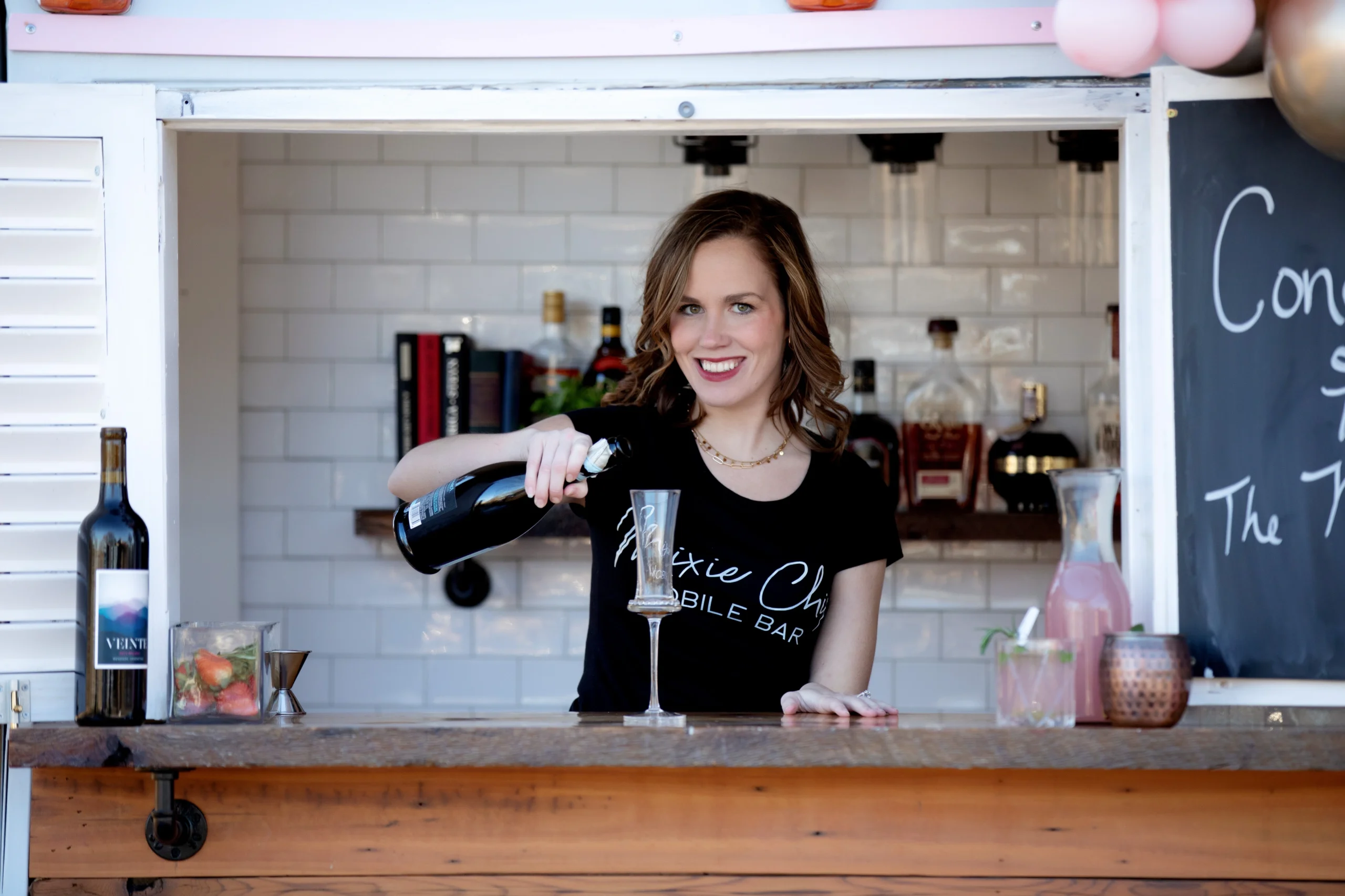 Samantha O’Brien, co-owner of Mixie Chix Mobile Bar, serving guests from the vintage trailer bar at an event in Fort Worth, Texas.